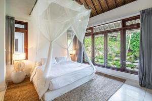 a bedroom with a bed with a mosquito net at VillaJewel Bali in Dalung