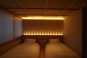 名古屋Ryokan Miyoshi的小型客房配有两张床,光线充足
