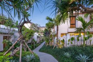 a walkway through the courtyard of a building with palm trees at La Numa Villas Canggu in Canggu