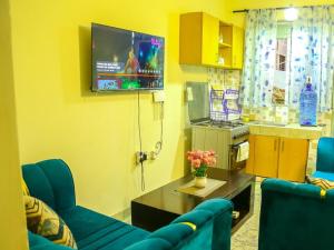 a living room with two blue chairs and a tv at Vee Apartment in Mombasa