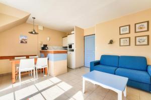 ein Wohnzimmer mit einer blauen Couch und einer Küche in der Unterkunft Résidence Belle Dune - maeva Home - Appartement 2 pièces 4 personnes - Sélection MAE-3751 in Fort-Mahon-Plage + 15 Fotos