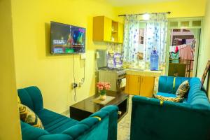a living room with two blue couches and a tv at Vee Apartment in Mombasa
