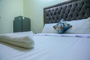 a bed with white sheets and a blue pillow on it at Vee Apartment in Mombasa