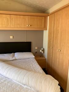 a bedroom with a white bed with wooden cabinets at Mersea Island at Lazeeedays in Colchester