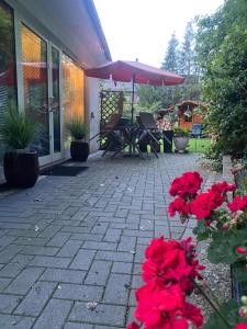 a patio with red flowers and an umbrella at Helles Appartment in Bremen