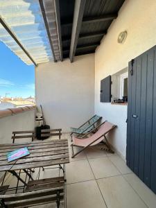a room with benches and a table and a balcony at Appartement cosy Le Bohème, à 300m des plages LOCAMARGUE in Saintes-Maries-de-la-Mer