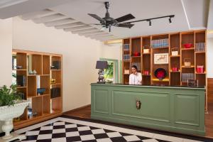 a woman standing at a counter in a room with wooden shelves at Modi Estate, Meerut - AM Hotel Kollection in Meerut