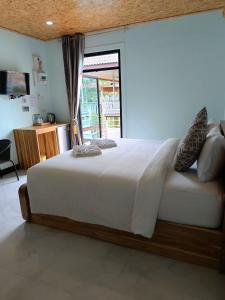 a bedroom with a large white bed with a window at Tanaporn resort bangsaphan in Bang Saphan