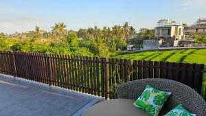 une chaise en rotin sur un balcon avec une clôture dans l'établissement Araya Luxe Villa, à Munggu