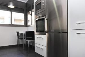 een keuken met een koelkast en een tafel met stoelen bij AT014 A pocos metros de la playa, equipamiento completo, piscina comunitaria in Torredembarra