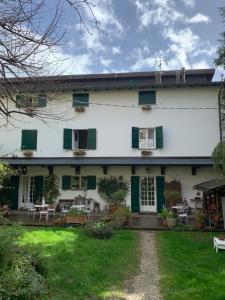 a white house with green shutters and a yard at Villa Fedora in Lizzano in Belvedere