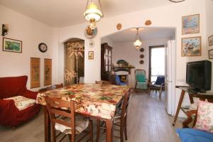 Un comedor con una mesa con sillas y un televisor. en Villetta bifamiliare nel verde a Pietrasanta, en Pietrasanta 6 fotos más