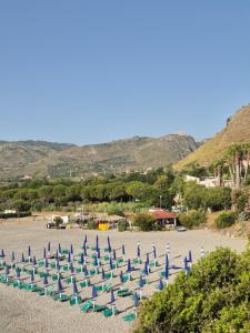 eine Reihe von Strandstühlen und Sonnenschirmen an einem Strand in der Unterkunft Hotel Guardacosta in Diamante
