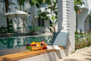 a basket of fruit on a table next to a pool at Secret House Boutique Hoi An in Hoi An