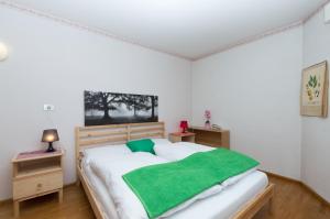 a bedroom with a large white bed with a green blanket at Chalet Center Pic in Ortisei