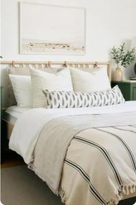 a bedroom with a bed with white sheets and pillows at Kindly Light Beach House, Borth-y-Gest in Porthmadog