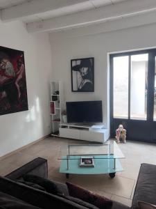 Una sala de estar con televisión y una mesa de centro de cristal. en La Maison Perrin, en Aigues-Mortes