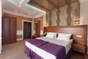 een slaapkamer met een groot bed met een houten hoofdeinde bij Chocolatier Hotel in Krasnodar