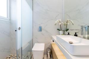 a white bathroom with a sink and a toilet at Jacuzzi Luxpenthouse PFaliro in Athens +47 photos
