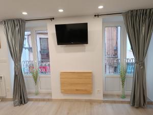 a living room with two windows and a flat screen tv at Casa El Papamoscas in Burgos