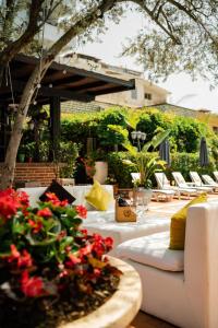 un patio con un sofá blanco, sillas y flores en Vila Belvedere, en Durrës