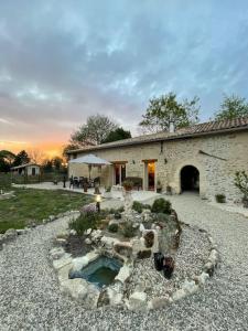 a stone house with a pond in the yard at Gite spacieux - 3 chambres - Calme et charmant in Cubnezais