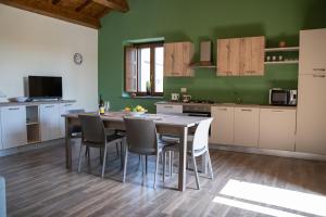 a kitchen with a table and chairs and green walls at Casa Badia in Santa Venerina