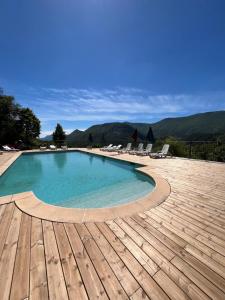 a swimming pool with chairs and a wooden deck at Les Ricoux in Montfroc