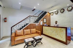 a man standing at a counter in a lobby with a couch at Hotel A. K. International - Fort in Mumbai