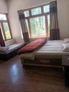 Un dormitorio con dos camas y dos ventanas. en Skara Homes, en Leh