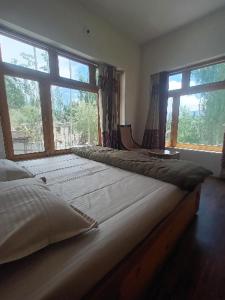 Un dormitorio con dos camas y una gran ventana. en Skara Homes, en Leh