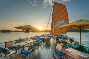 a deck of a boat with tables and umbrellas at Paradise Luxury Sails Cruise in Ha Long