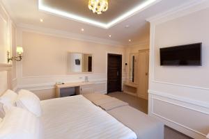a bedroom with a white bed and a television at Chocolatier Hotel in Krasnodar