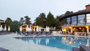 a pool with chairs and umbrellas next to a building at Santa Marina Holiday Village - Purple Harmony Sea view in Sozopol