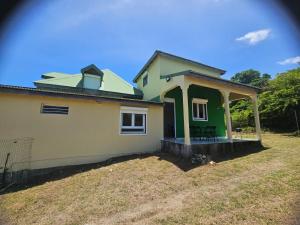a small green and white house with a yard at Tranquillité et repos in Sainte-Anne
