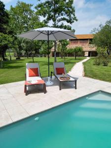 two chairs and an umbrella next to a swimming pool at CHATEAU LAURIGA in Thuir