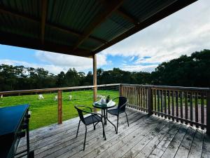a deck with a table and chairs and a view of a field at GORGE Chocolates Tiny House in Kennedys Creek