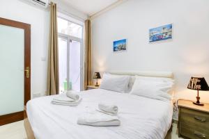 a bedroom with a white bed with towels on it at NR Retreat in Il-Gżira