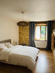 a bedroom with a bed and a brick wall at La Maison Cosy in Frontenay