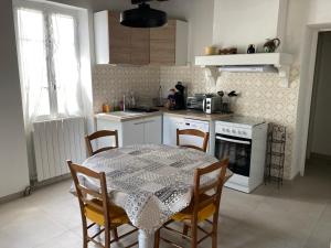 a kitchen with a table and chairs and a kitchen with a stove at Chez la Mamé in Alès