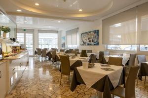 a restaurant with tables and chairs in a room at Hotel Bristol in Caorle