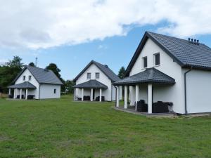 un grupo de tres casas blancas en un campo en Sosnówka - domki nad morzem, en Kopalino
