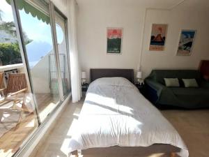 Un dormitorio con una cama y un sofá y una ventana. en Le TIKAL studio 4 pers, centre-ville port, clim, en La Grande-Motte