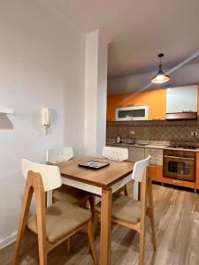 a kitchen with a wooden table and white chairs at Coastal Comfort Apartament in Golem