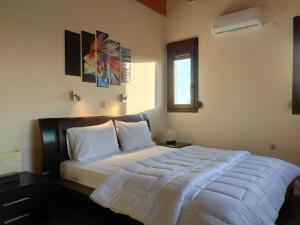 a bedroom with a large bed with white sheets at Luxury Villa konstantina! in Yerakiní