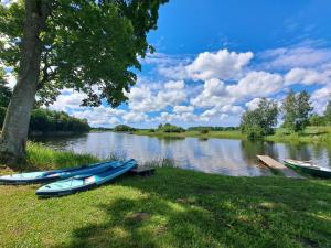 three canoes sitting on the grass next to a river at Brīvdienu māja Straumēni in Pāle