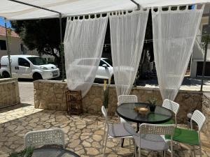 a patio with a table and chairs under a white canopy at Apartmani Luciano in Novalja