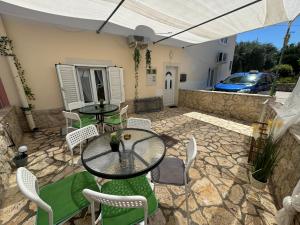 a patio with a table and chairs and a car at Apartmani Luciano in Novalja