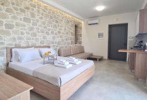 a bedroom with a bed and a stone wall at Studios Rosmari in Áyioi Pándes
