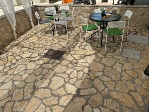 a patio with tables and chairs on a stone floor at Apartmani Luciano in Novalja